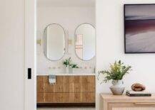 A white barn door on black rails is finished with oil rubbed bronze hardware opens to a reveal a beautifully appointed master bathroom.