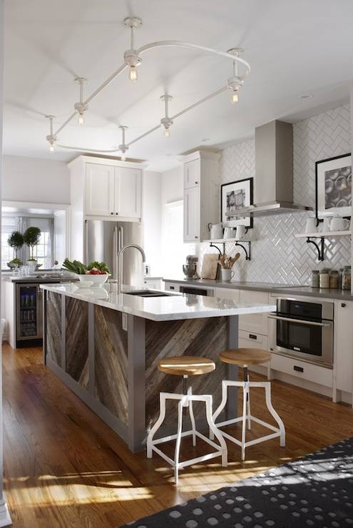 Stunning kitchen with gray paint color, Ikea kitchen cabinets with Silestone Grey Expo countertops, barnboard kitchen island with calcutta marble countertop, herringbone tile backsplash, white shelves flanking induction cooktop, white swivel stools from Morba, glass-front wine cooler and vintage shower enclosure lighting.