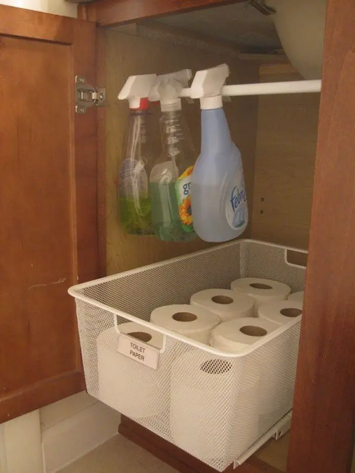 tension rod under bathroom sink with toilet paper and spray bottles