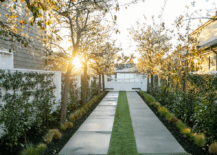 A row of trees lines a large concrete walkway accented with concrete pavers and grass pavers.