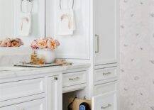 Hairdryer cabinet adds a unique pull out drawer feature to a white vanity washstand. The master bath vanity is completed with polished nickel hardware and marble countertops styled with decor for a sophisticated finish.