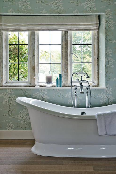 Blue French master bathroom boasts a blue floral wallpaper lined with a spa tub and a vintage style tub filler.