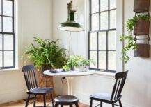 Dining space features a green accordion style lantern that illuminates a marble tulip table with vintage black spindle chairs under wooden ceiling beams.