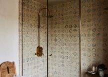 A walk in shower with a glass and brass enclosure boasts an eye-catching vintage brass shower kit mounted to Moroccan style surround tiles over matching floor tiles.