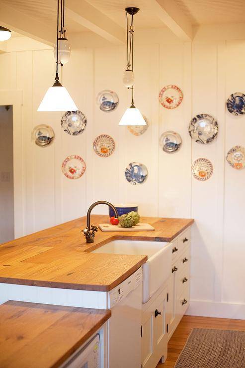 Fun plate arrangement in cozy seaside cottage with reclaimed wood countertops & white shaker cabinets.