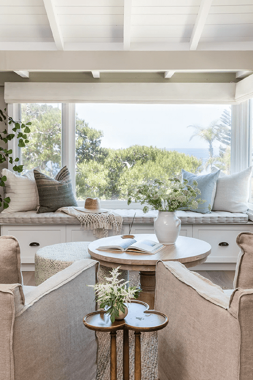 Natural light streams in from windows located over a built-in window seat fitted with drawers donning oil rubbed bronze cup pulls and topped with a light gray cushion.