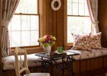 Vintage style bedroom features a black bamboo accent table with white French cane seat chair next to a built in window seat with rabbit print cushion under a rabbit print valance with matching curtains.