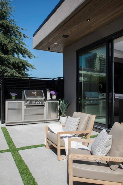 Stylish patio features stainless steel mini bbq kitchen, blond teak outdoor chairs with taupe cushions atop concrete pavers.