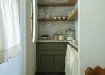 Kitchen features a small green pantry with black and white marble checkered floor tiles and L shaped wooden shelves over gray marble offset backsplash tiles.