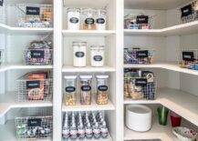 White U-shaped kitchen pantry boasts white modular shelves stocked with labeled wire snack baskets and cereal canisters.