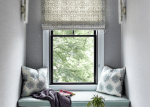 Window seat nook design with gray wallpaper features green seat cushions and blue block print pilows.