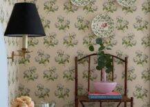 Cottage bedroom with decorative wall plates on a shabby chic floral wallpaper wall.