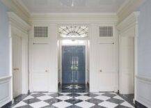 Black and white marble harlequin floor tiles lead to a vestibule boasting a a leaded glass transom window and a glossy blue French door.