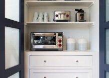 Kitchen pantry with blue bi-fold pantry doors and frosted glass panels. Small nickel knobs accent white shaker cabinet drawers under white stacked shelves displaying pantry essentials.