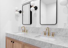 marble countertop black frame mirror bathroom globe wall scones and gold faucets