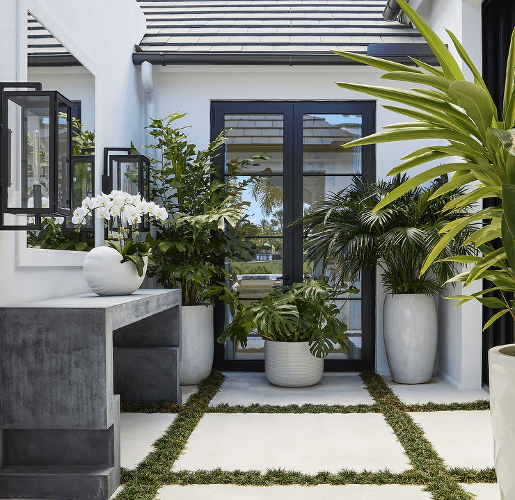 Chic patio boasts a concrete Greek key console table paired with a white mirror.