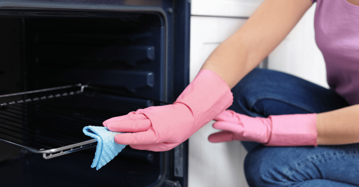 Person wearing pink gloves cleaning oven racks.