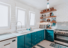 White and blue kitchen with wooden floating shelves.