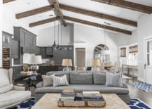 A neutral color living room with vaulted ceiling and wood beams.