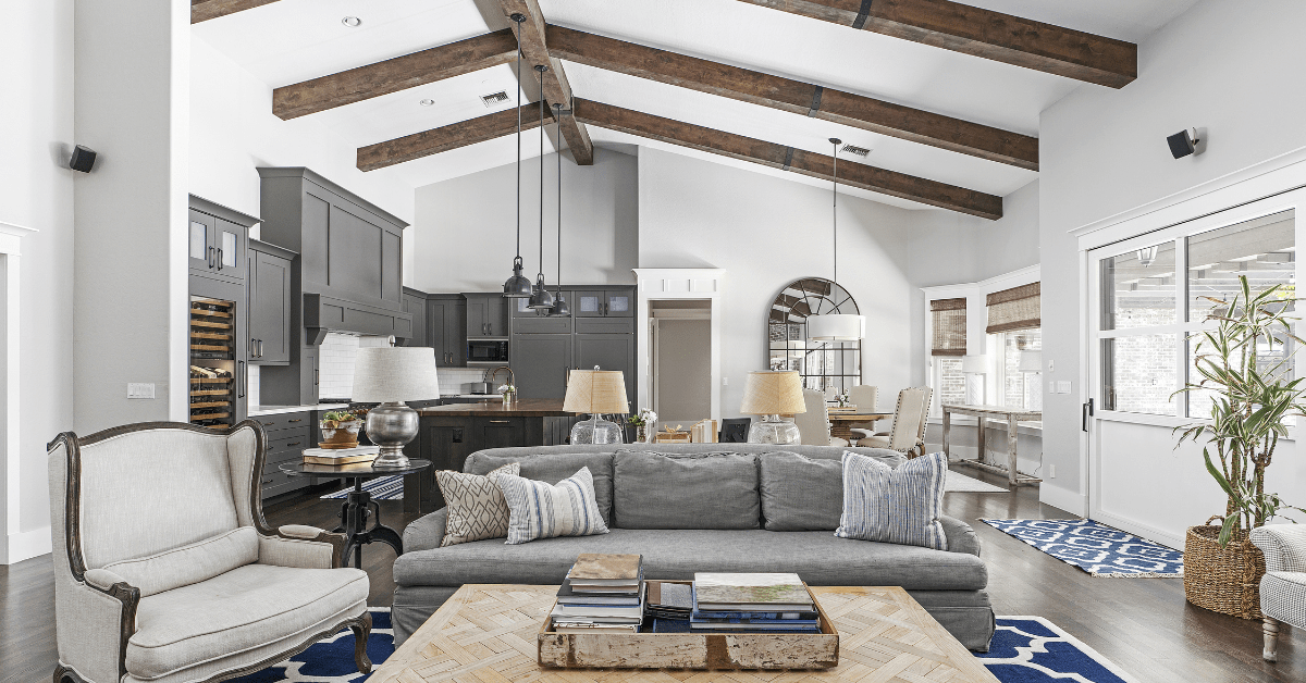 A neutral color living room with vaulted ceiling and wood beams.