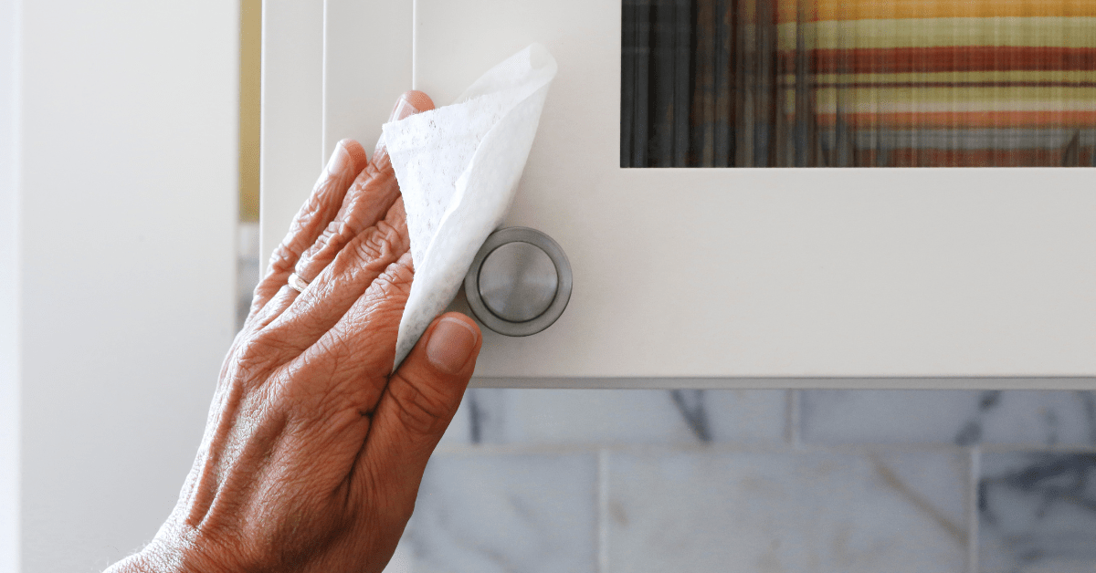 Hand wiping down kitchen cabinet.