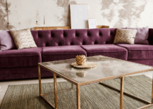 Purple couch in a living room with a coffee table with metallic frame.