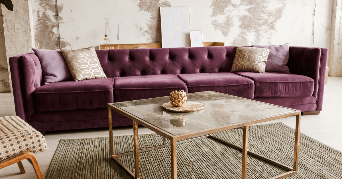 Purple couch in a living room with a coffee table with metallic frame.