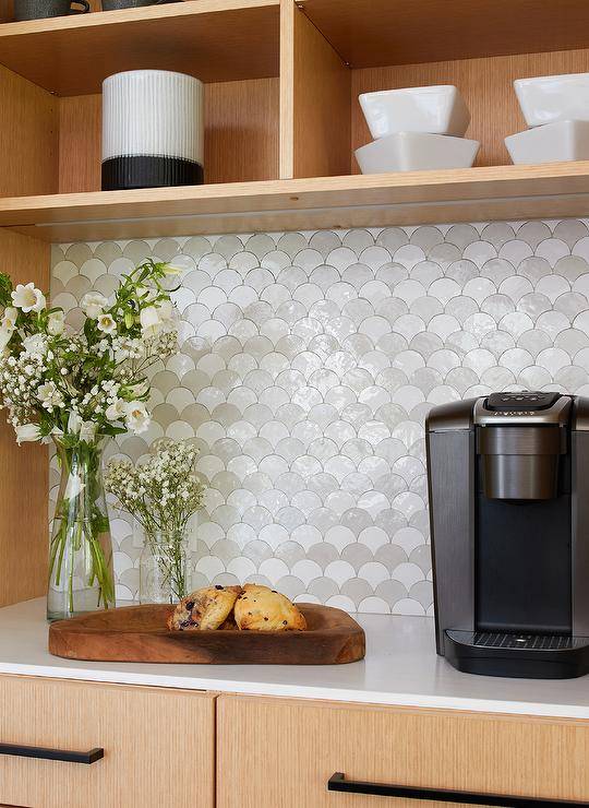 Kitchen features a coffee station with white and gray scale tiles under beige shelving.