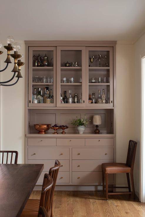 A light brown built-in hutch and cabinets are inset into a beautifully designed dining room wall.