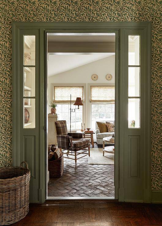 A black plaid accent chair sits on red brick herringbone pavers in a beautiful styled cottage living room.