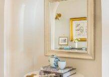 Entryway features an arched alcove with a silver leaf beaded mirror over a round marble top accent table.