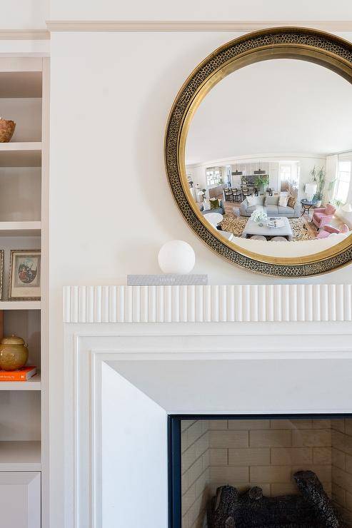 Living room features a round leopard print mirror over a modern white fireplace mantel.