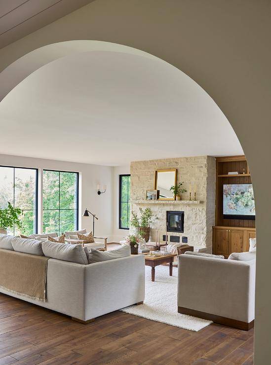 A white sofa sits on a white rug facing a farmhouse coffee table.