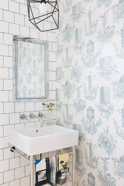 Chrome and porcelain sink designed with an inset framed medicine cabinet and square white tiles finished with vintage white and blue Toile de Jouy wallpaper in a transitional powder room.