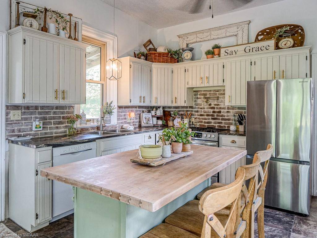 country kitchen wide shot with butcher block island cream cabinets decorated on top