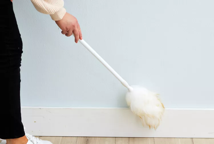 woman dusting baseboards with duster