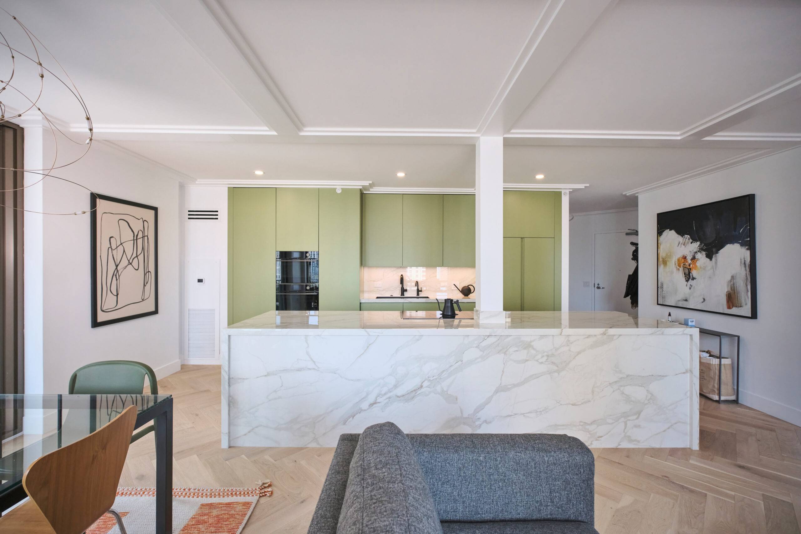 Open concept living room kitchen with sage green walls.