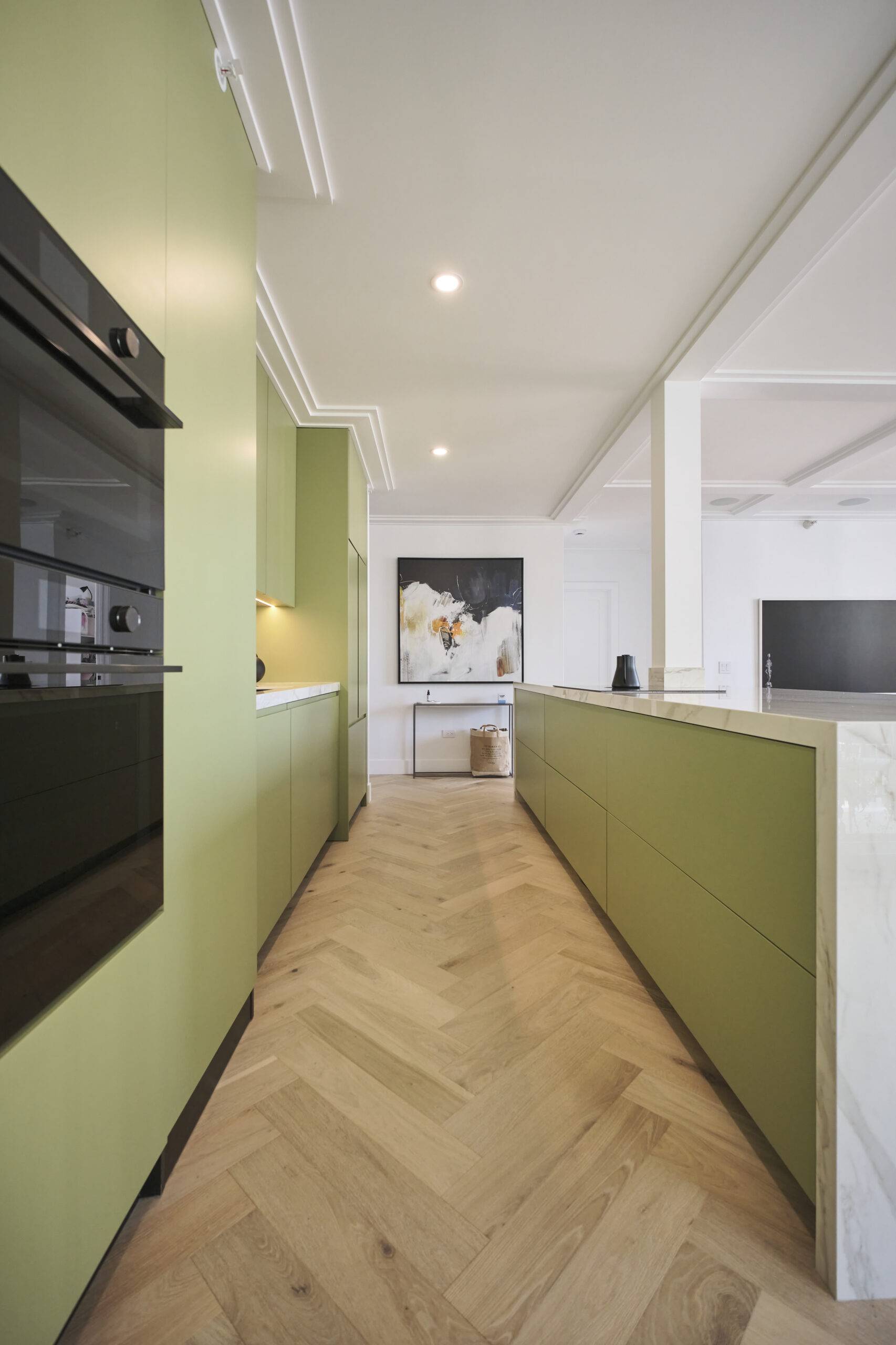 Sage green kitchen with white accents and light wooden floors.