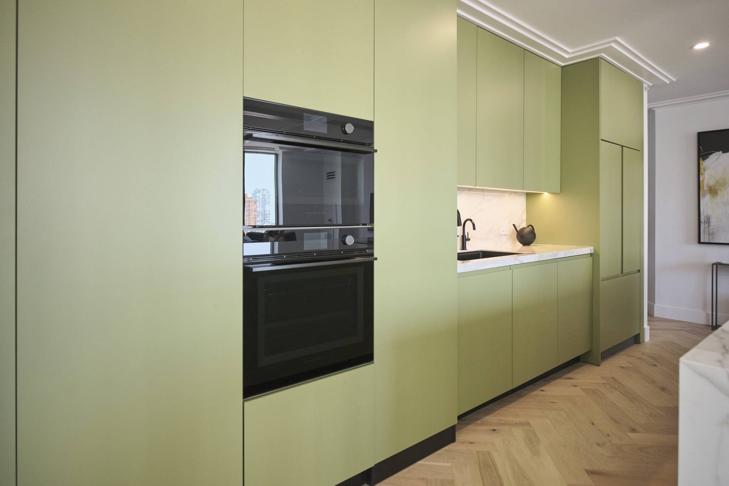 Black modern oven in a sage green kitchen.