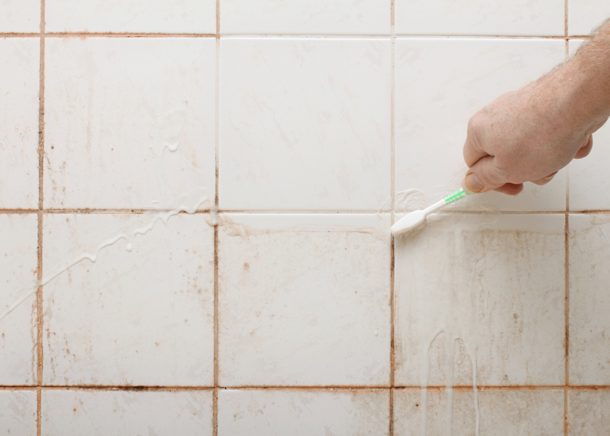 scrubbing dirty shower with toothbrush