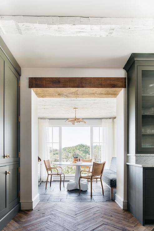 A rattan chandelier illuminates a round white dining table paired with brown rope dining chairs in a keeping room.