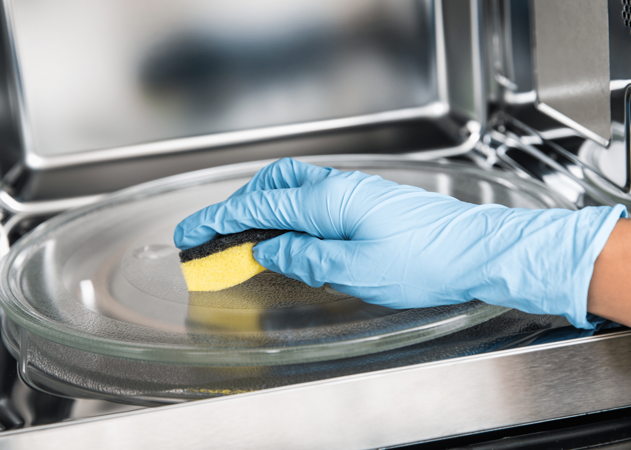 close up of cleaning microwave with sponge