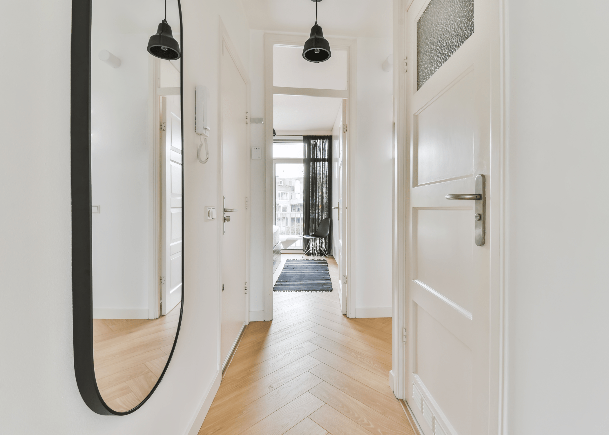 long hallway with black frame statement mirror and white walls.