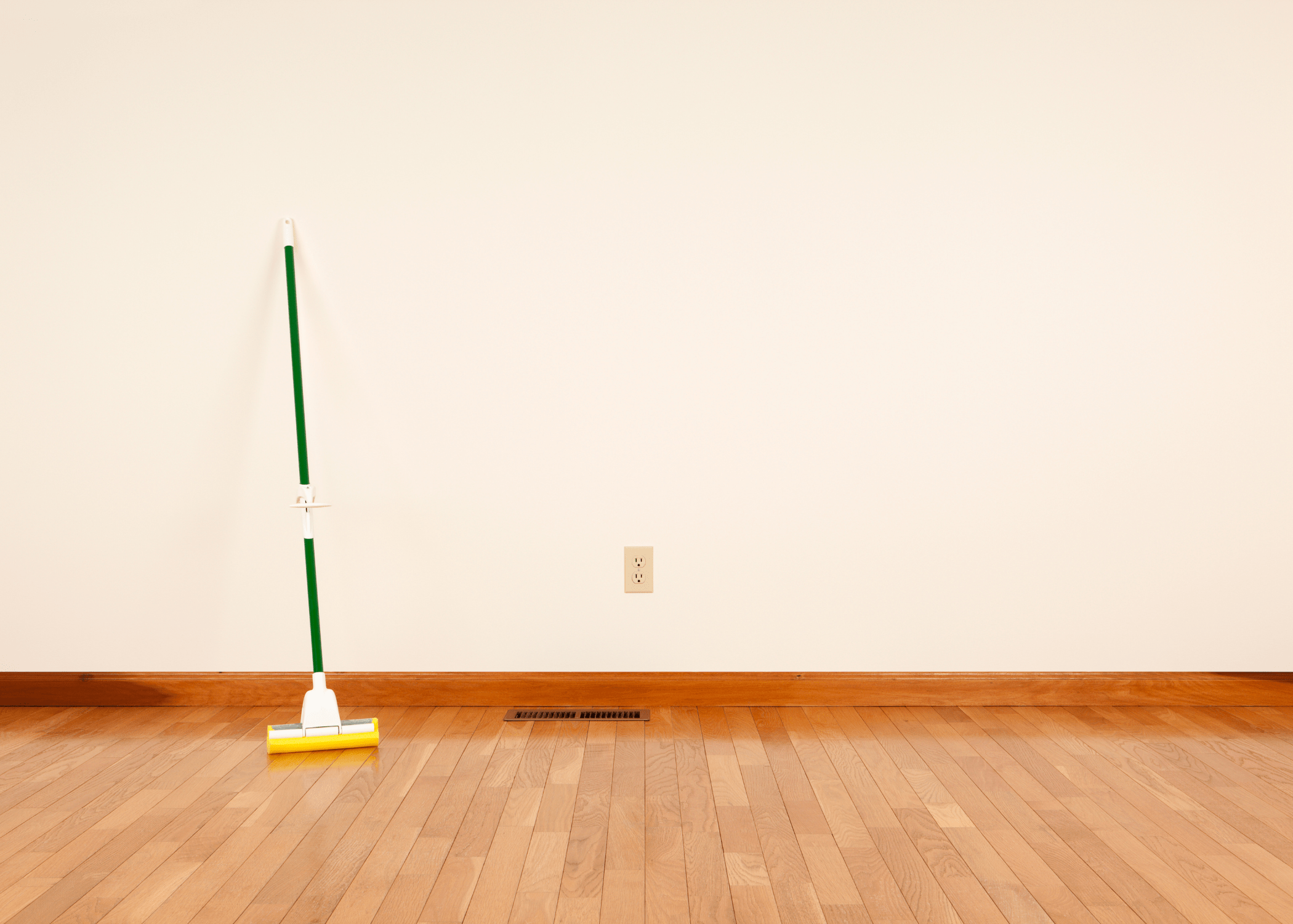 mop leaning up against white wall in an empty room