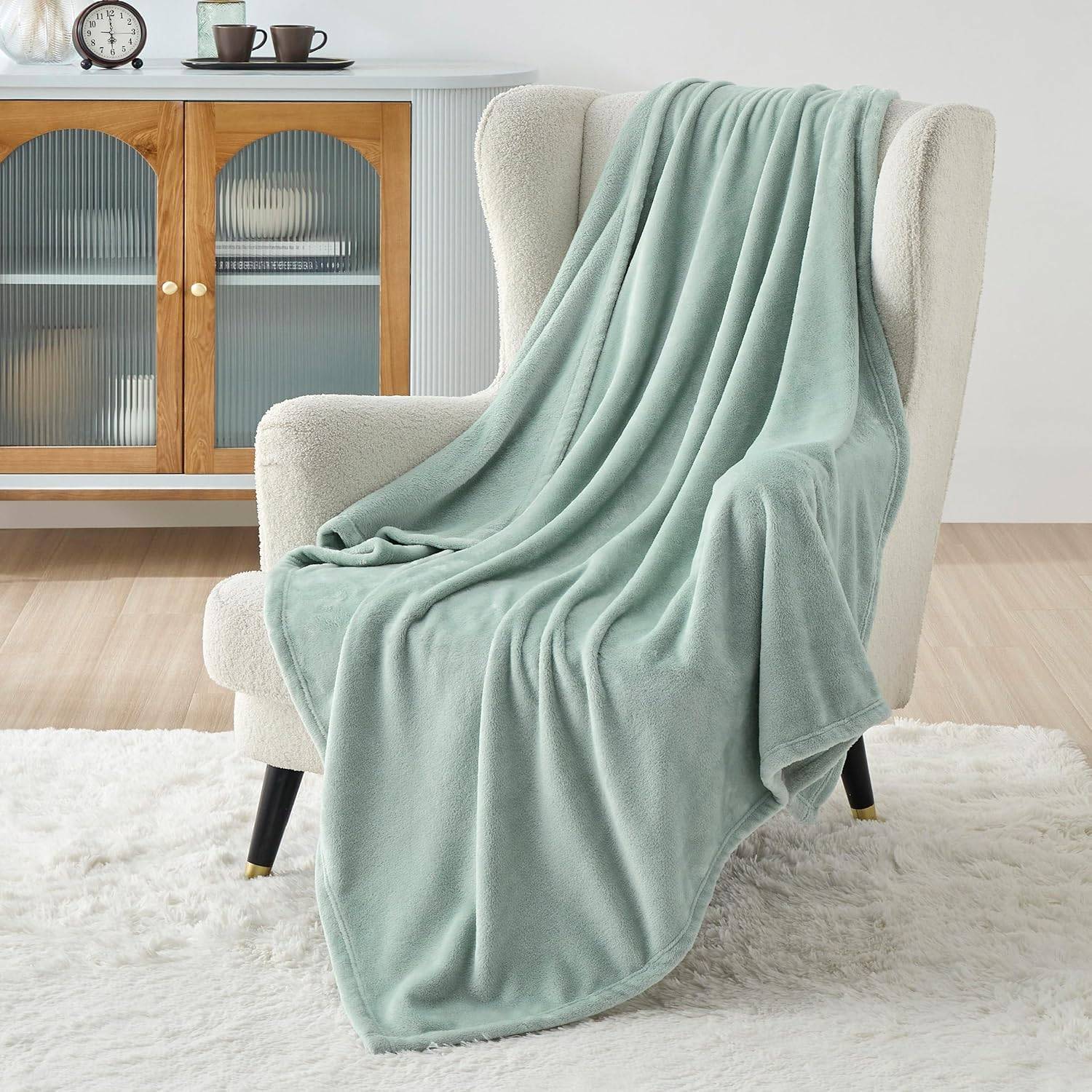 sage green blanket on white chair