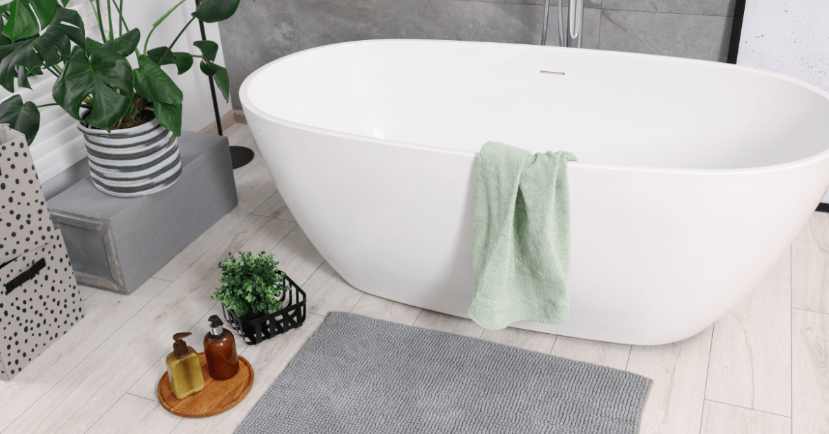 White bathroom tub fronted by a grey matt.