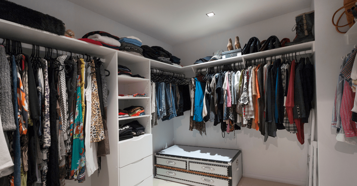 Inside of a walk in closet with hung clothes.