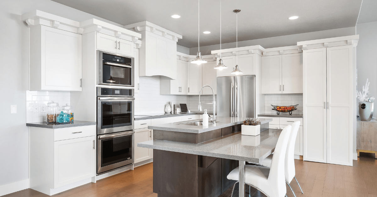 Overhead lighting on top of island flanked by white kitchen cabinets.