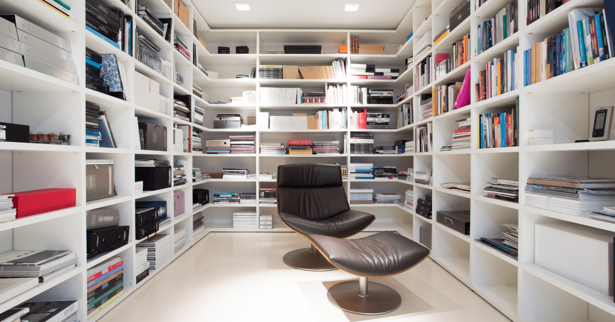 White floor to ceiling bookshelves around a chair.