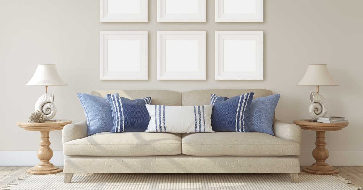 Beige couch with coast themed throw pillows.